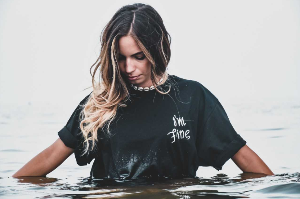 Young girl wearing a black shirt and standing in water.