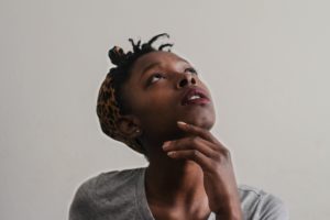 African American girl in a gray shirt looking upward in a thinking postion.
