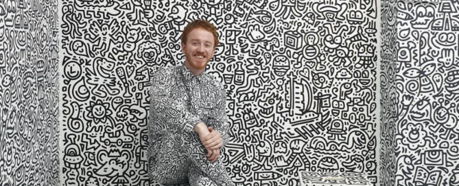 Sam Cox (AKA Mr. Doodle) posing in front of his art in Korea.