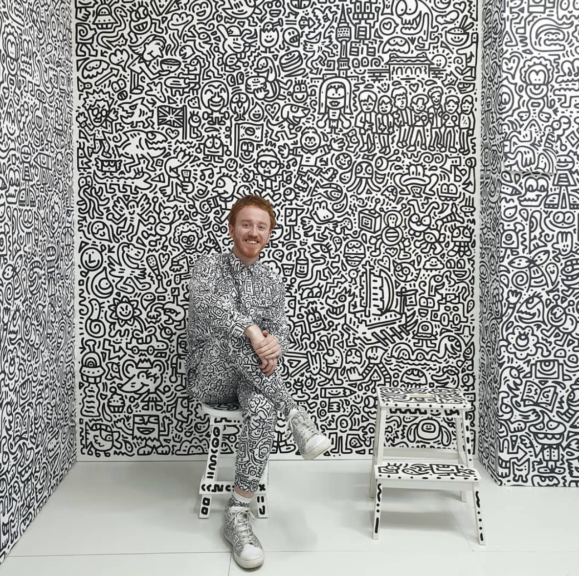 Sam Cox (AKA Mr. Doodle) posing in front of his art in Korea.